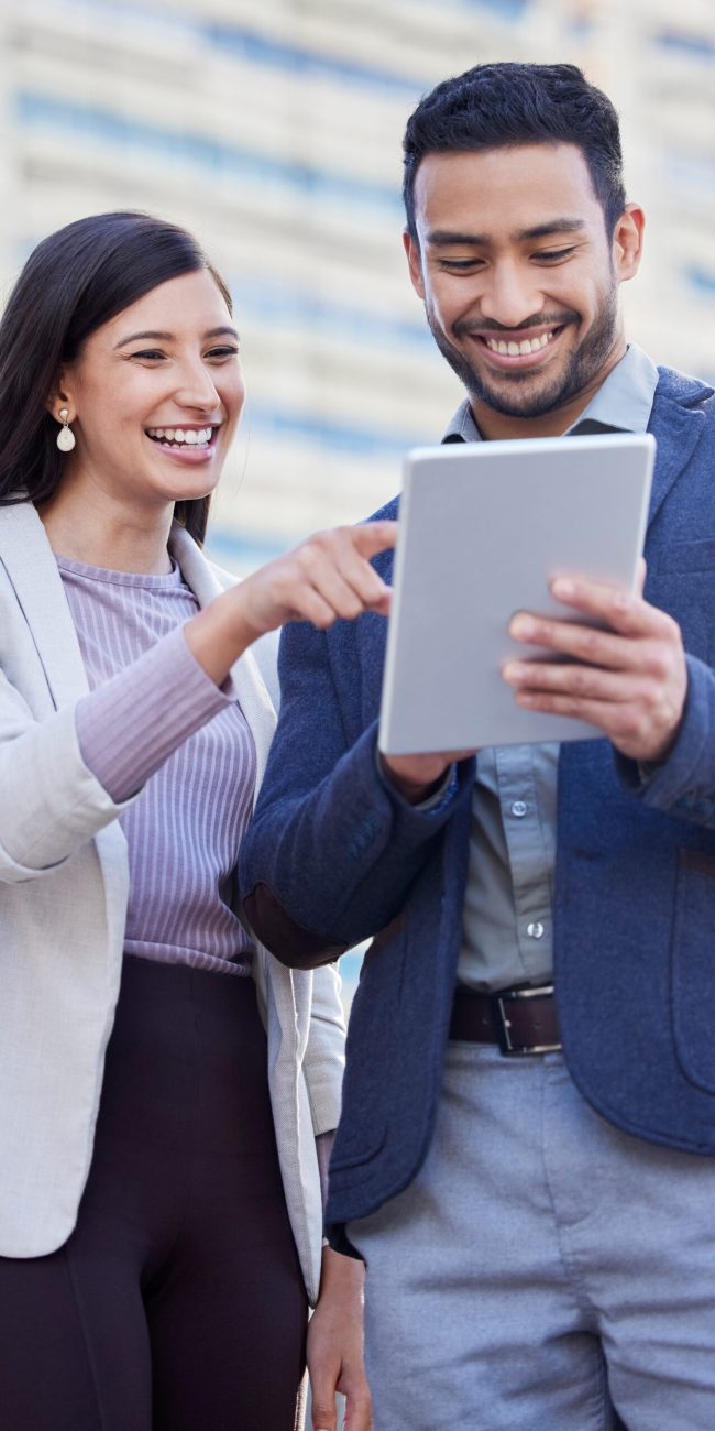 two coworkers using ipad smiling