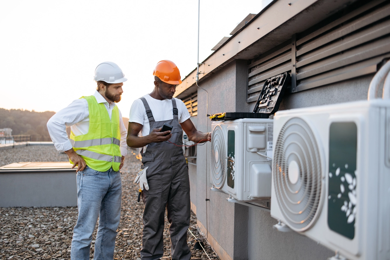 repairmen with multimeter fixing air conditioner