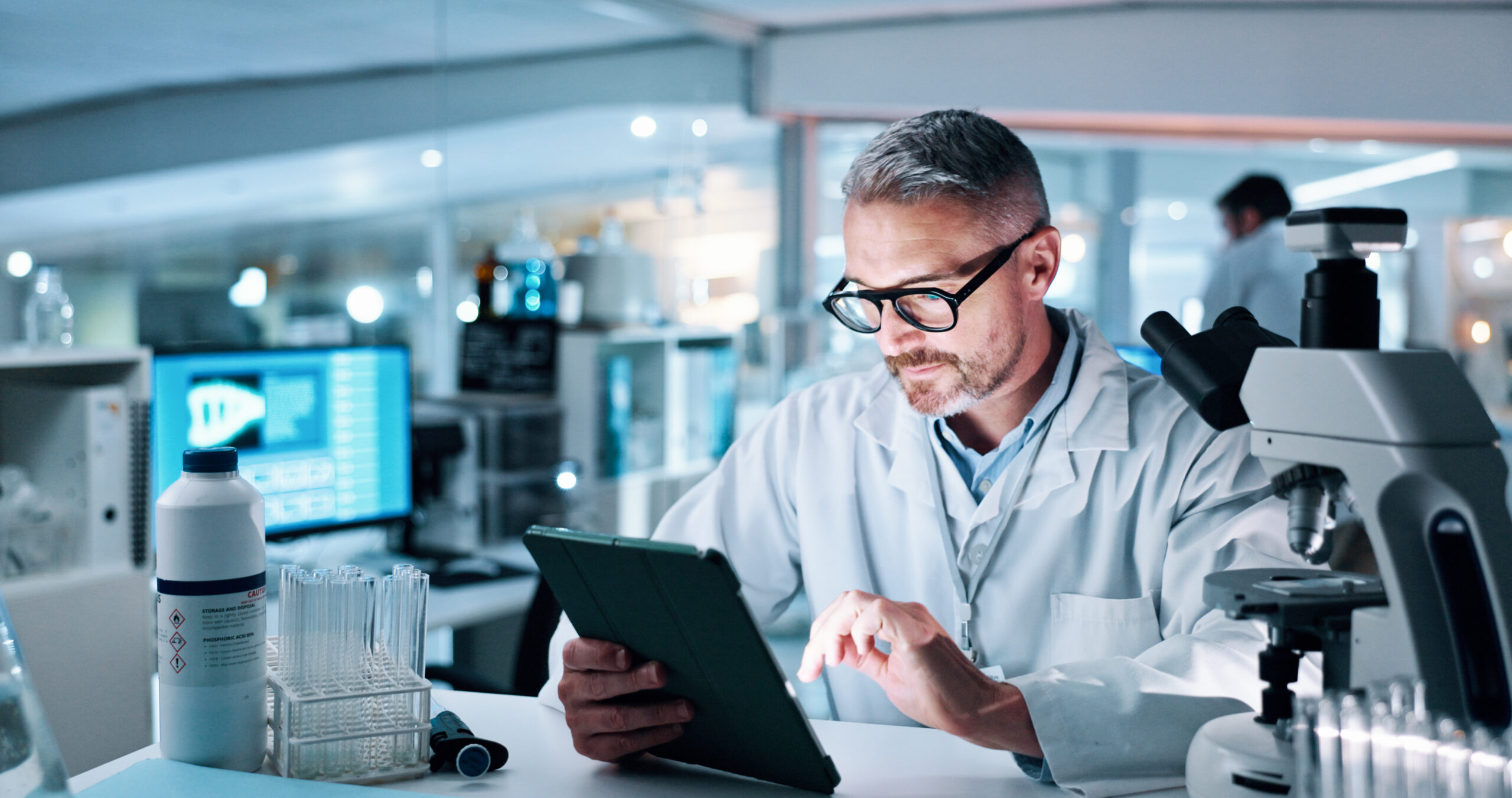 Scientist analyzing research data on a tablet in a laboratory, using a cloud-based platform for faster study and analysis.